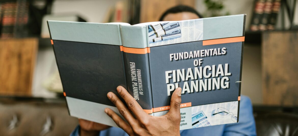A professional individual in a suit reading 'Fundamentals of Financial Planning' indoors.