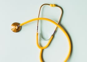 Top view of yellow medical stethoscope placed on white surface during coronavirus pandemic